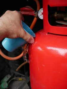 Pouring warm water on red gas bottle